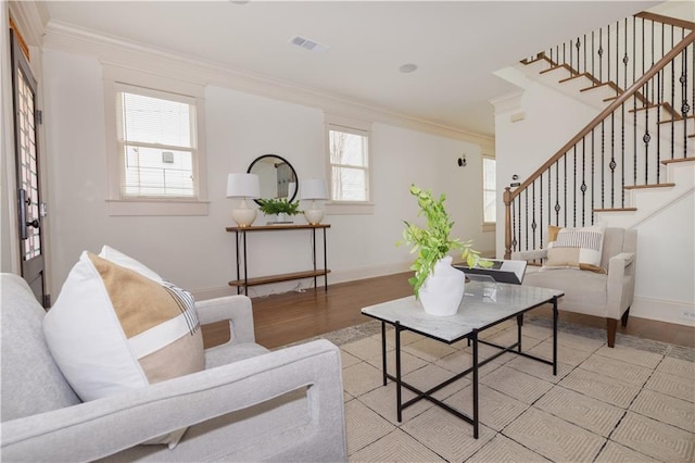 living room featuring visible vents, light wood-style floors, and ornamental molding