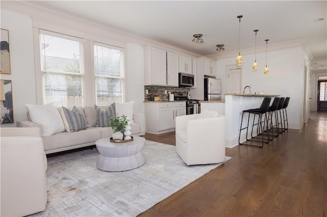 living area with dark wood-style flooring, a wealth of natural light, and ornamental molding