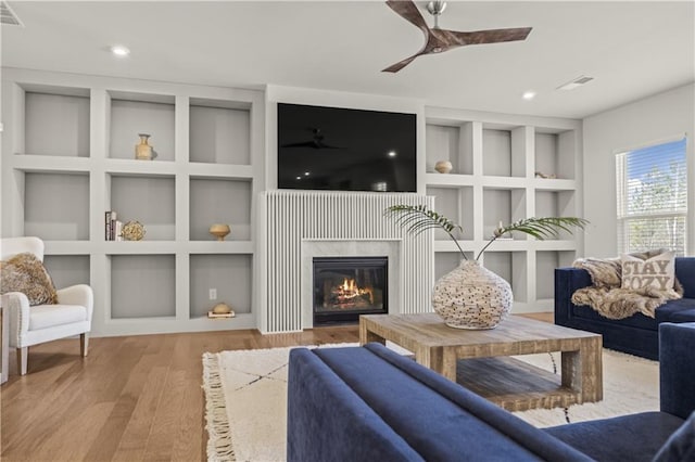 sitting room with ceiling fan, wood-type flooring, and built in features