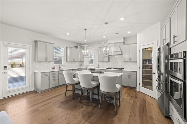 kitchen featuring a breakfast bar, a center island, gray cabinets, pendant lighting, and stainless steel appliances