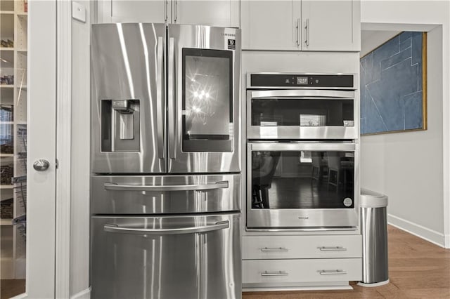 kitchen featuring dark wood-type flooring, appliances with stainless steel finishes, and white cabinets