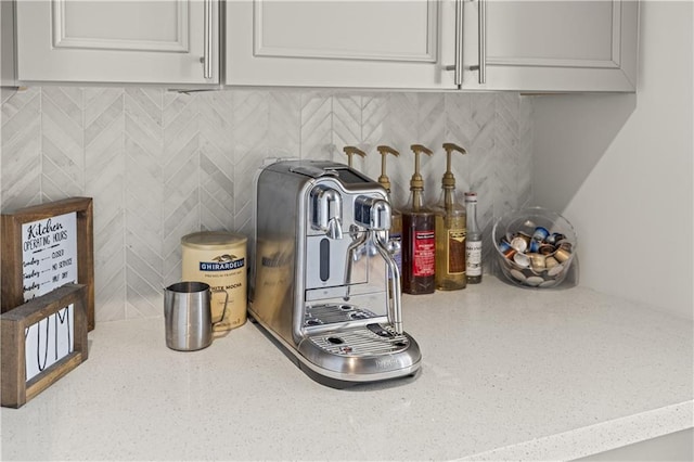 interior details featuring light stone counters, tasteful backsplash, and white cabinets