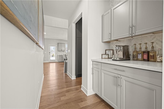 bar with light wood-type flooring and decorative backsplash