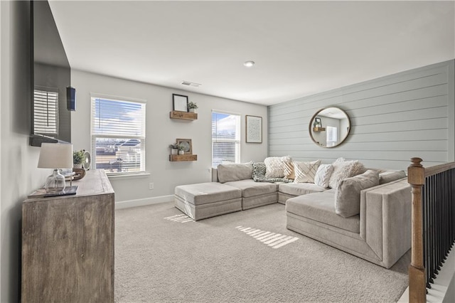 living room featuring plenty of natural light, light colored carpet, and wood walls