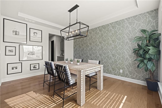 dining room featuring a raised ceiling, wood-type flooring, and an inviting chandelier