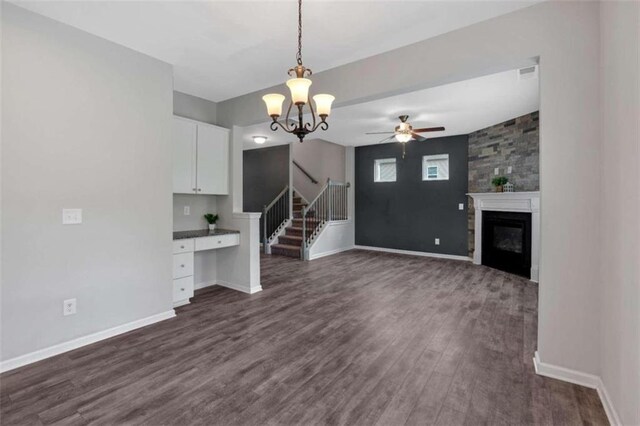 unfurnished living room featuring ceiling fan with notable chandelier and dark wood-type flooring