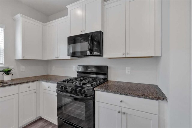 kitchen with hardwood / wood-style flooring, black appliances, dark stone countertops, and white cabinets