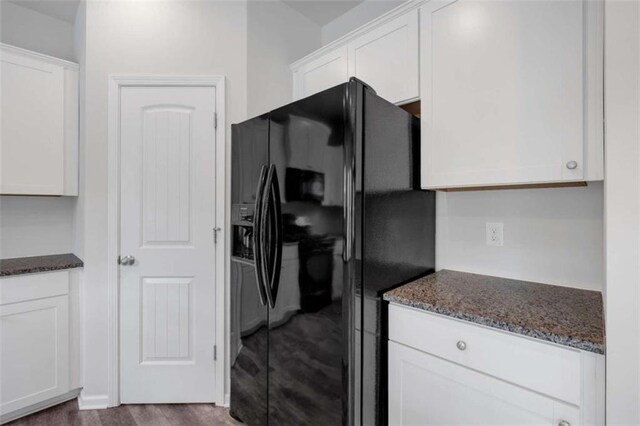 kitchen featuring dark stone counters, black refrigerator with ice dispenser, dark hardwood / wood-style flooring, and white cabinets