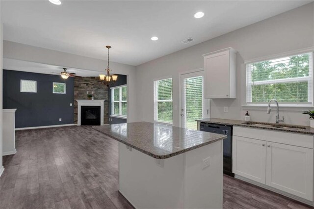 kitchen featuring white cabinets, sink, plenty of natural light, dishwasher, and a large fireplace