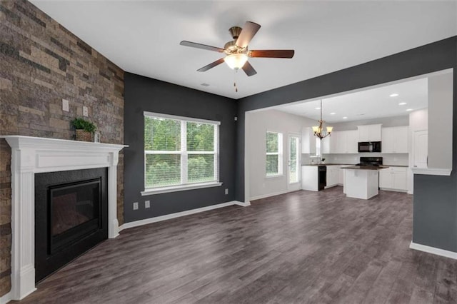 unfurnished living room featuring ceiling fan with notable chandelier and dark hardwood / wood-style flooring