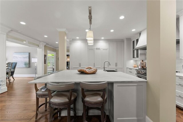 1539 Berkeley Ct, Gainesville, GA 30501 - kitchen featuring custom range hood, a sink, ornamental molding, a breakfast bar area, and a kitchen island with sink