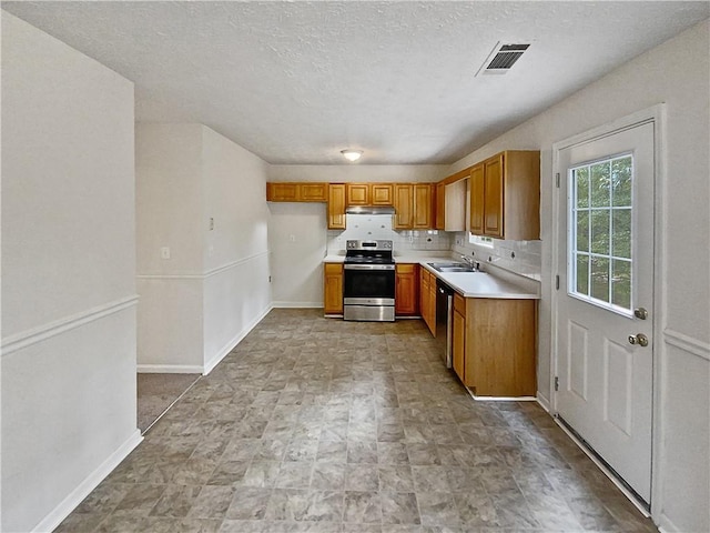 kitchen featuring appliances with stainless steel finishes, decorative backsplash, a textured ceiling, and sink