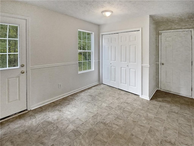 unfurnished bedroom with multiple windows, a textured ceiling, and a closet