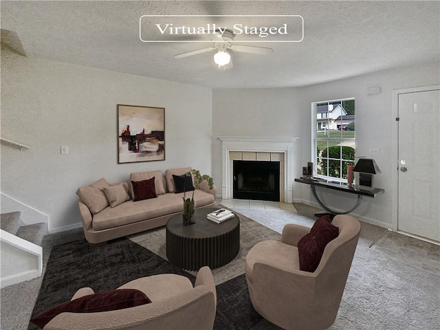 living room with ceiling fan, a textured ceiling, and a fireplace