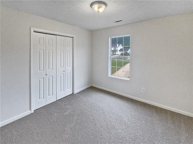 unfurnished bedroom with carpet, a closet, and a textured ceiling