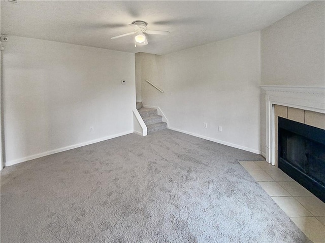 unfurnished living room featuring ceiling fan, a tile fireplace, and carpet floors