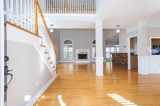 unfurnished living room featuring decorative columns, a wealth of natural light, a high ceiling, and hardwood / wood-style flooring