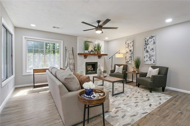 living area featuring light wood finished floors, baseboards, visible vents, a fireplace, and recessed lighting