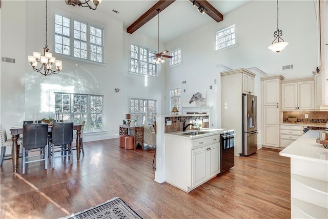 kitchen featuring dishwasher, a high ceiling, stainless steel fridge, decorative backsplash, and beam ceiling