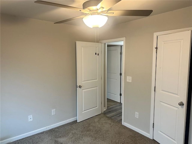 unfurnished bedroom featuring ceiling fan, dark colored carpet, and baseboards