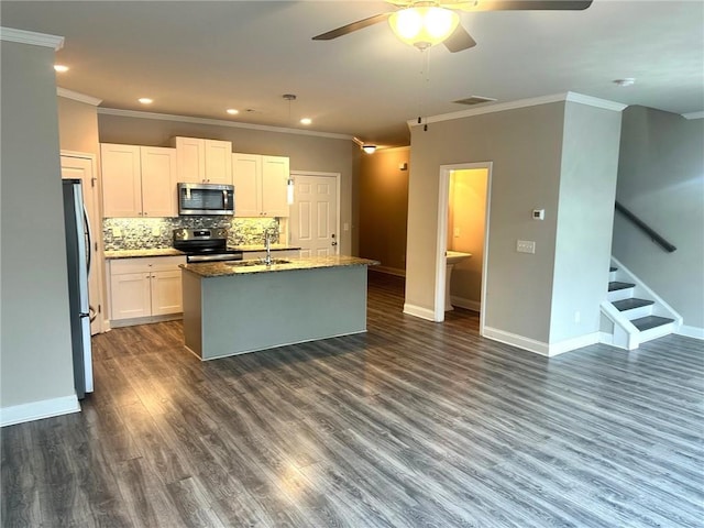 kitchen featuring visible vents, white cabinets, appliances with stainless steel finishes, dark stone countertops, and a center island with sink