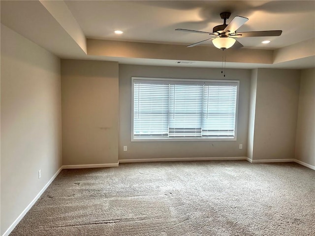 empty room with carpet, a tray ceiling, baseboards, and recessed lighting