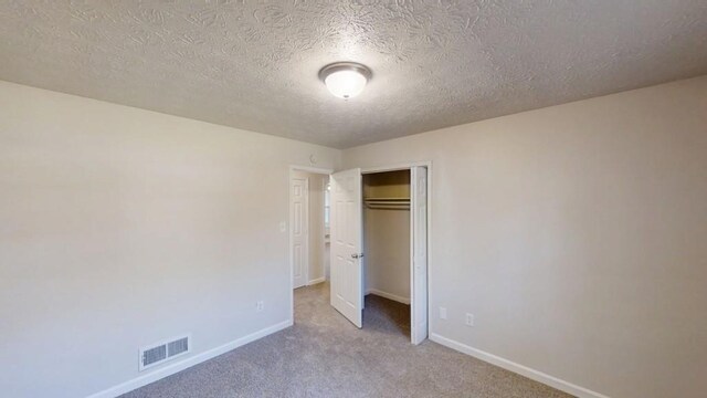 3359 Mansfield Ln, Snellville, GA 30039 - unfurnished bedroom featuring visible vents, a textured ceiling, a closet, carpet floors, and baseboards