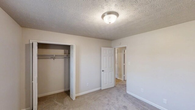 3359 Mansfield Ln, Snellville, GA 30039 - unfurnished bedroom featuring baseboards, a closet, carpet floors, and a textured ceiling