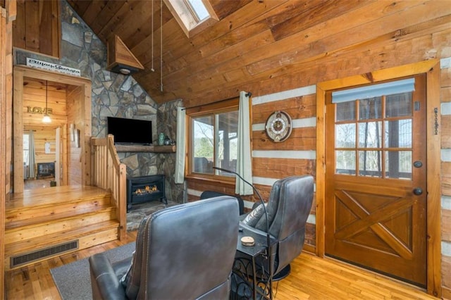 193 Alm Ln, Ellijay, GA 30540 - living area featuring a stone fireplace, a skylight, vaulted ceiling, wood finished floors, and wooden walls