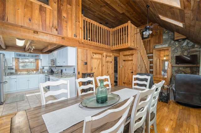 193 Alm Ln, Ellijay, GA 30540 - dining room featuring wood ceiling with exposed beams, a ceiling fan, light wood-style flooring, wood walls, and high vaulted ceiling