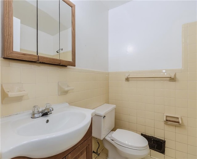 bathroom featuring vanity, tile walls, and toilet