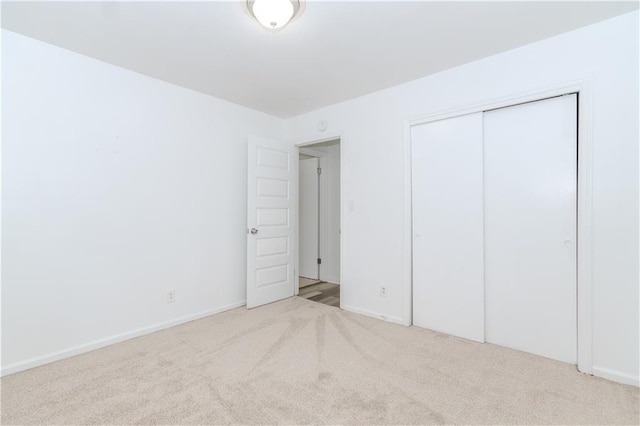 unfurnished bedroom featuring light colored carpet and a closet