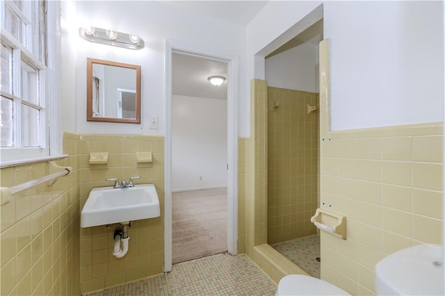 bathroom featuring tile walls, sink, toilet, and tiled shower