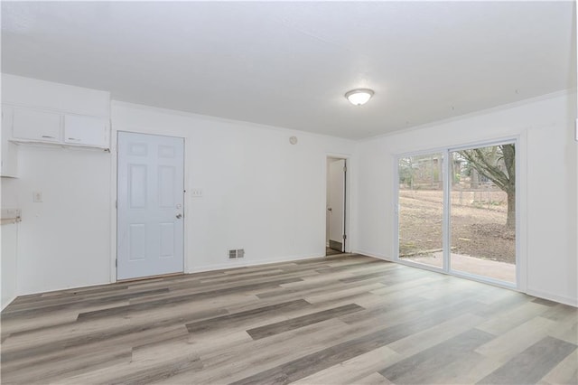 spare room featuring ornamental molding and light wood-type flooring