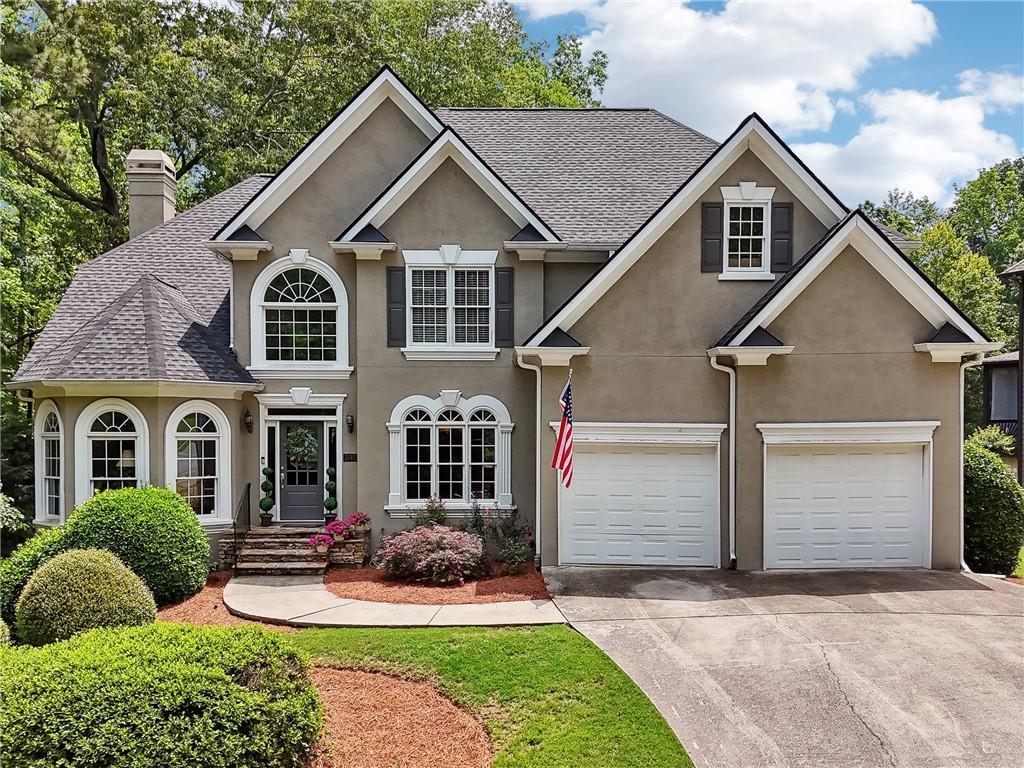 2485 Millwater Xing, Dacula, GA 30019 - traditional-style home featuring stucco siding, concrete driveway, a chimney, a garage, and a shingled roof