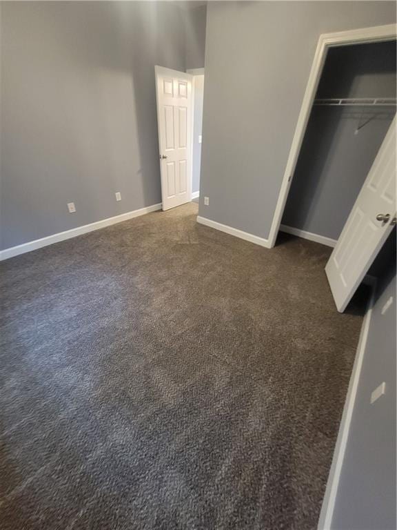 unfurnished bedroom featuring dark carpet and a closet