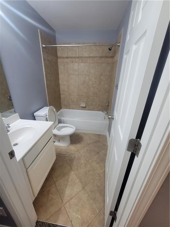 full bathroom with tile patterned floors, vanity, toilet, and tiled shower / bath combo