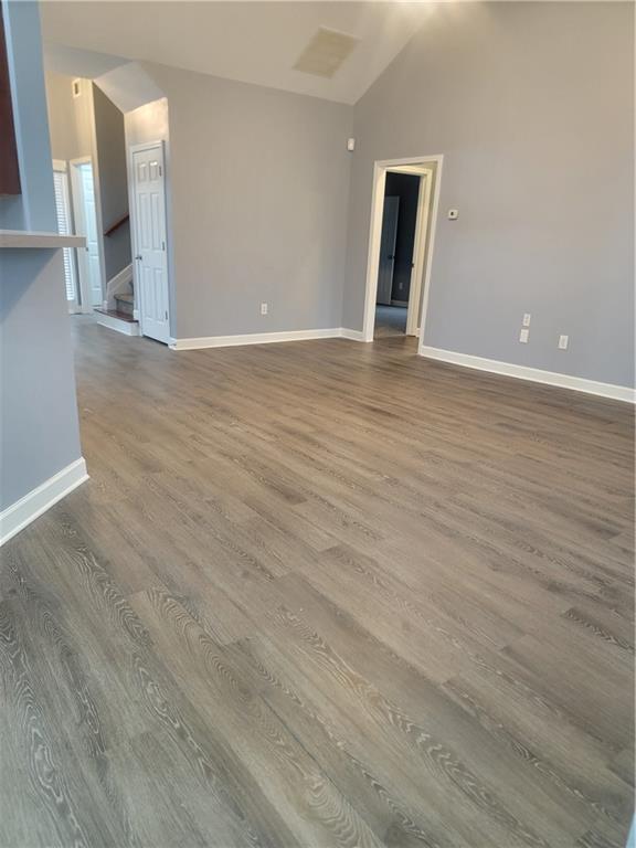 unfurnished room featuring vaulted ceiling and hardwood / wood-style floors