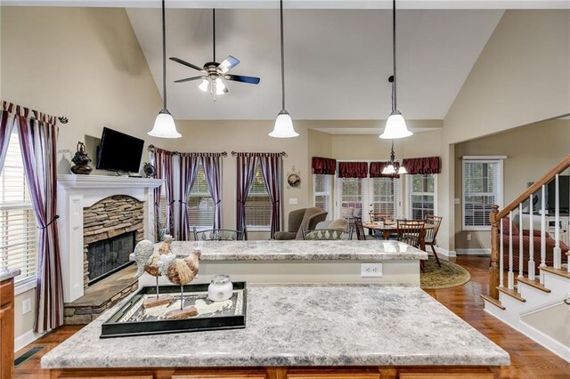 kitchen with decorative light fixtures, a fireplace, ceiling fan with notable chandelier, and high vaulted ceiling