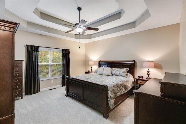 carpeted bedroom featuring ceiling fan and a raised ceiling