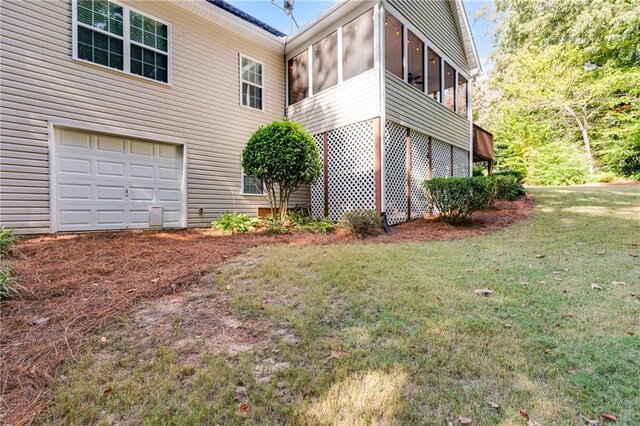 view of property exterior with a garage, a sunroom, and a lawn