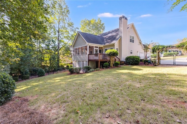 back of property with a deck, a sunroom, and a lawn