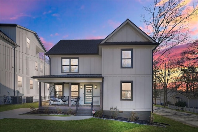 modern farmhouse style home featuring a porch, a shingled roof, a front lawn, central air condition unit, and board and batten siding