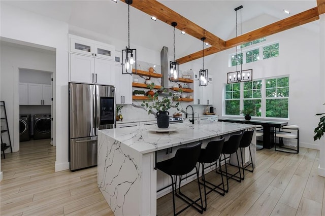 kitchen with beamed ceiling, open shelves, tasteful backsplash, stainless steel fridge, and separate washer and dryer