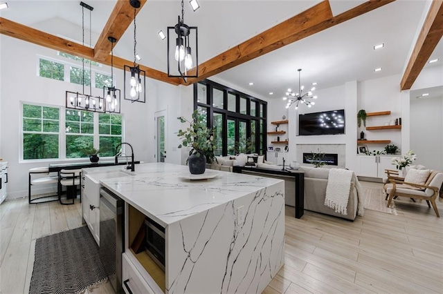 kitchen featuring beam ceiling, an inviting chandelier, and a glass covered fireplace