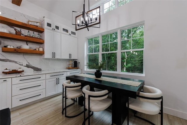 dining area with baseboards, a chandelier, and light wood finished floors