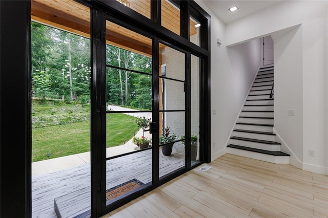 doorway featuring light wood finished floors, visible vents, stairway, and baseboards