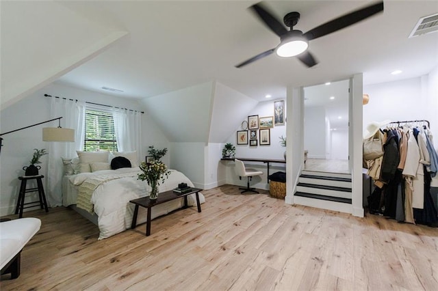 bedroom featuring visible vents, light wood-style flooring, a ceiling fan, and vaulted ceiling