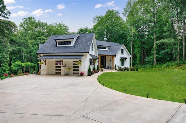 modern farmhouse style home featuring a front lawn, a garage, driveway, and a shingled roof