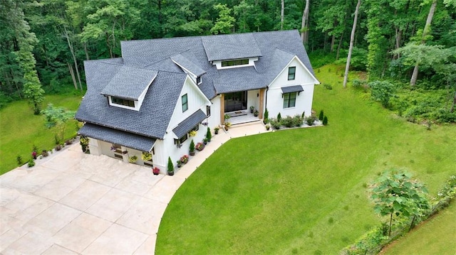 modern farmhouse with a front yard, driveway, and roof with shingles